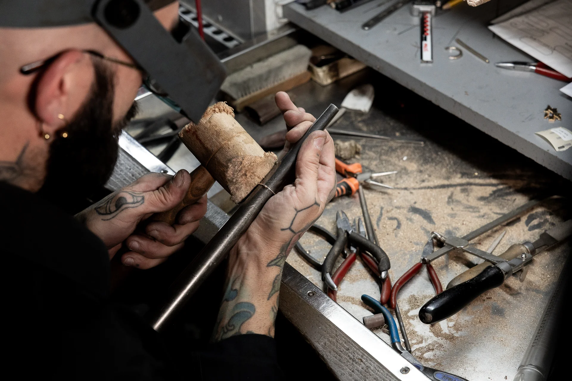 Orafo al banco da lavoro mentre modella manualmente un gioiello con strumenti tradizionali