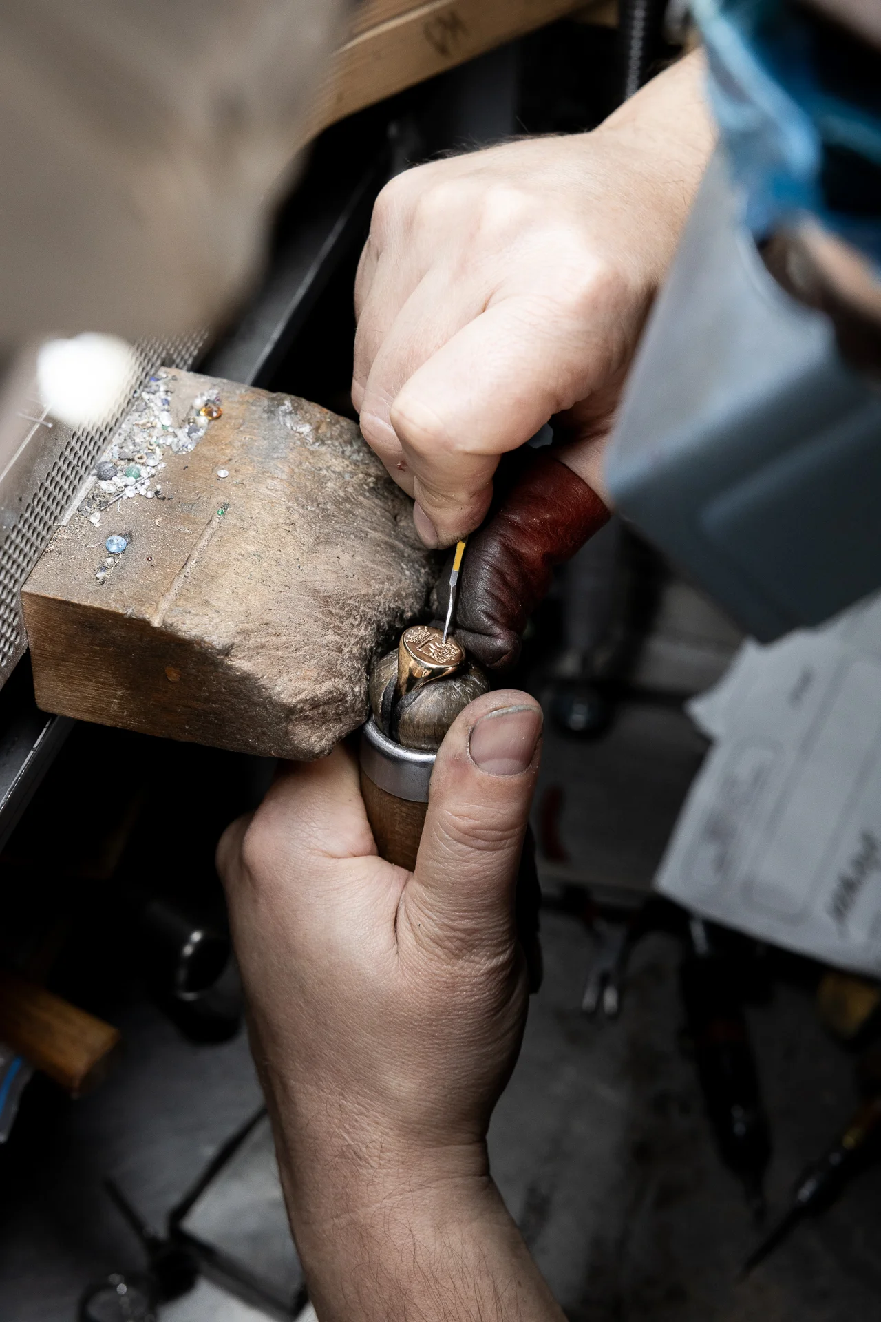 Artigiano orafo mentre incide a mano un anello in oro nel laboratorio