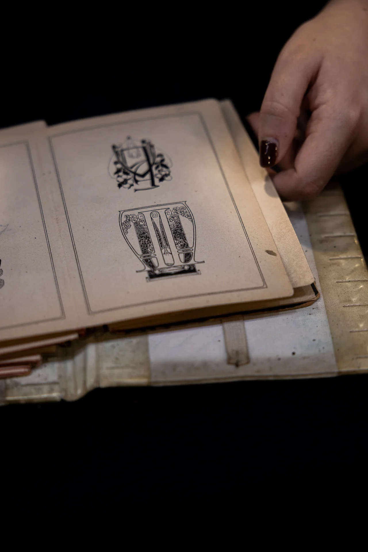 Mano che sfoglia un archivio di disegni storici per gioielli artigianali